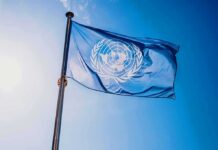 United Nations flag waving on a pole against clear blue sky
