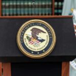 Department of Justice podium with seal in front of bookshelves