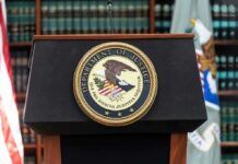 Department of Justice podium with seal in front of bookshelves