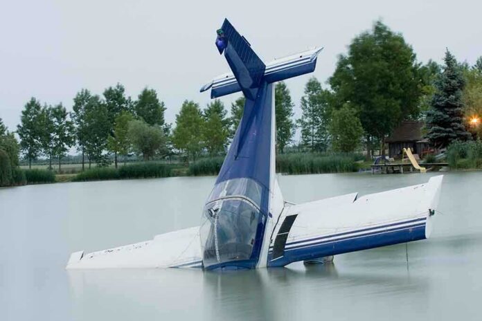 A submerged airplane partially in a lake with trees in the background