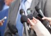 Microphones held toward a person in a suit