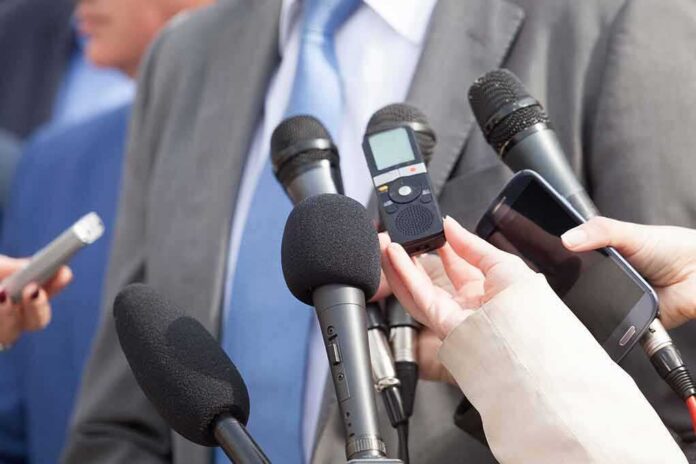 Microphones held toward a person in a suit