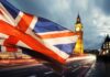 Union Jack flag waving with clock tower in London at dusk
