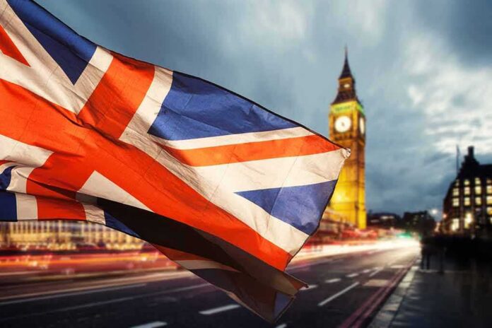 Union Jack flag waving with clock tower in London at dusk