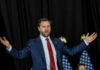 man in suit speaking with arms outstretched