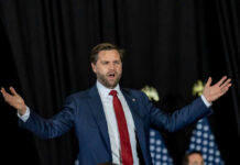 man in suit speaking with arms outstretched