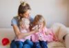 Mother comforting two young daughters on couch