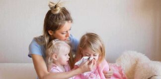 Mother comforting two young daughters on couch