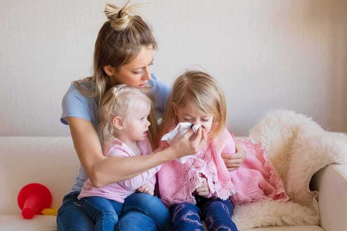 Mother comforting two young daughters on couch