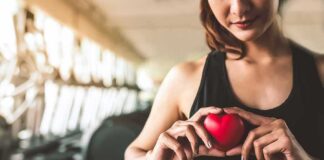 Woman in sportswear holding a red heart-shaped object at the gym