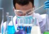 Scientist pipetting blue liquid into test tubes