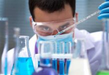 Scientist pipetting blue liquid into test tubes