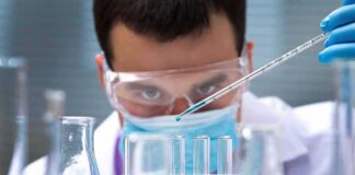 Scientist pipetting blue liquid into test tubes