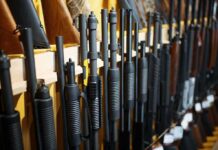 Shotguns and rifles lined up on a rack in a gun store