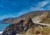 Coastal highway curving along rocky cliffs above blue ocean