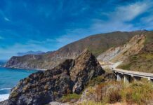 Coastal highway curving along rocky cliffs above blue ocean