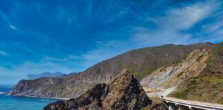 Coastal highway curving along rocky cliffs above blue ocean