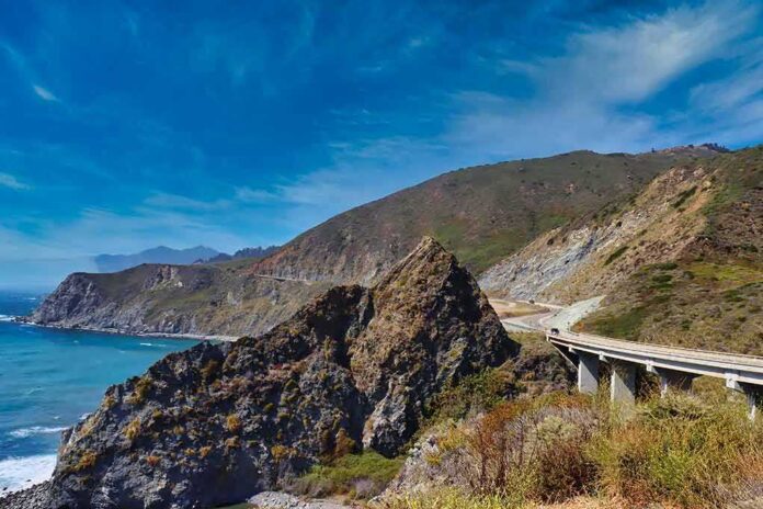 Coastal highway curving along rocky cliffs above blue ocean