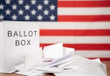 Ballot box with papers in front of an American flag