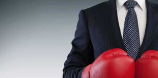 Businessperson in suit wearing red boxing gloves