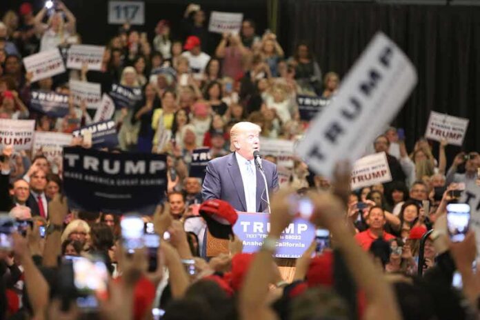 shutterstock_426567685 Donald Trump speaks at a rally podium as a large crowd cheers; Orel Hershiser, Ion Marin, and Billy Joe DuPree present