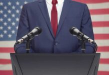 Speaker in suit at podium with microphones