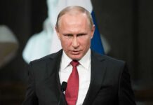 Vladimir Putin speaking at a podium with a microphone