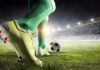 Soccer player in green socks about to kick a ball on a stadium field