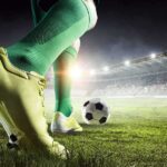 Soccer player in green socks about to kick a ball on a stadium field