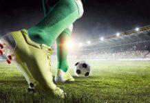 Soccer player in green socks about to kick a ball on a stadium field