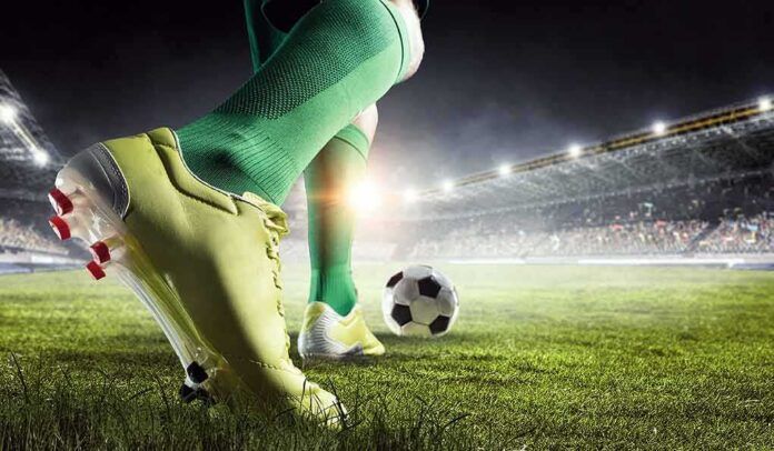 Soccer player in green socks about to kick a ball on a stadium field