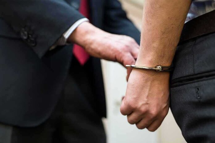 shutterstock_744392413 Handcuffed person being escorted by someone in a suit